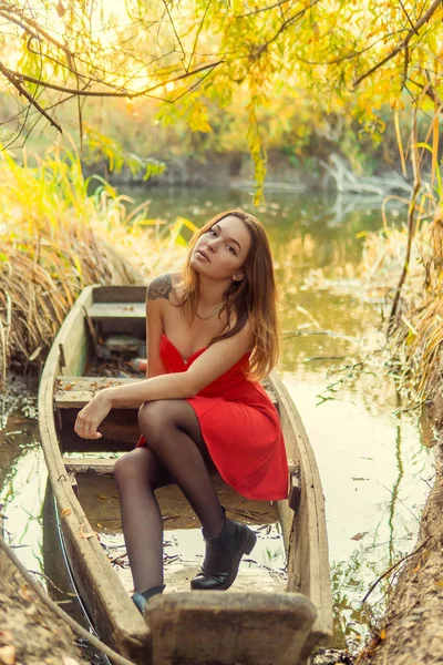 Uma mulher está posando na frente de uma câmera em um parque de outono. sessão de fotos de outono. Outono no parque . — Fotografia de Stock