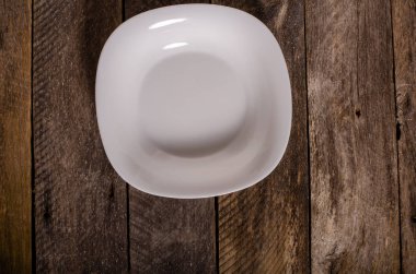 Kopya alanı ile ahşap arka plan üzerinde boş beyaz çanak ve beyaz masa örtüsü üst görünümü