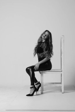 Çekici esmer güzellik sandalyede oturuyor.