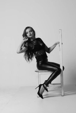 Çekici esmer güzellik sandalyede oturuyor.