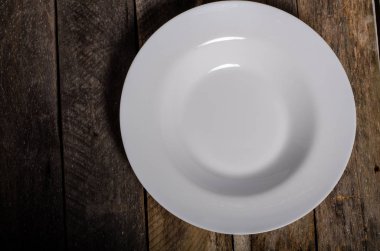 Kopya alanı ile ahşap arka plan üzerinde boş beyaz çanak ve beyaz masa örtüsü üst görünümü