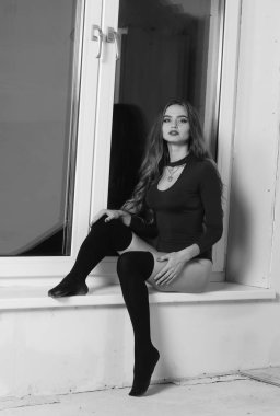 Büyük göğüslü seksi genç kadın. Siyah duvarda poz veren kız