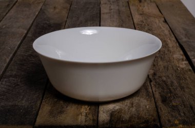 Kopya alanı ile ahşap arka plan üzerinde boş beyaz çanak ve beyaz masa örtüsü üst görünümü