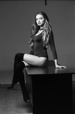 Büyük göğüslü seksi genç kadın. Siyah duvarda poz veren kız