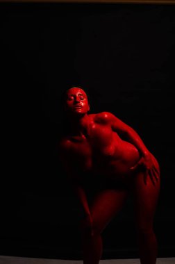 genç bir kızın yaratıcı portresi. Yüz kırmızı glitter boya ile boyanmıştır. Üçgen yüze çizilir. Siyah arka plan daki profilmodeli