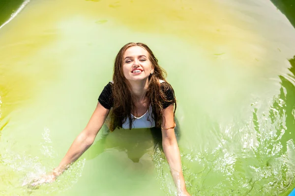 Beautiful female model dressed in long evening gowns, lies in the pool and sensually poses — Stock Photo, Image