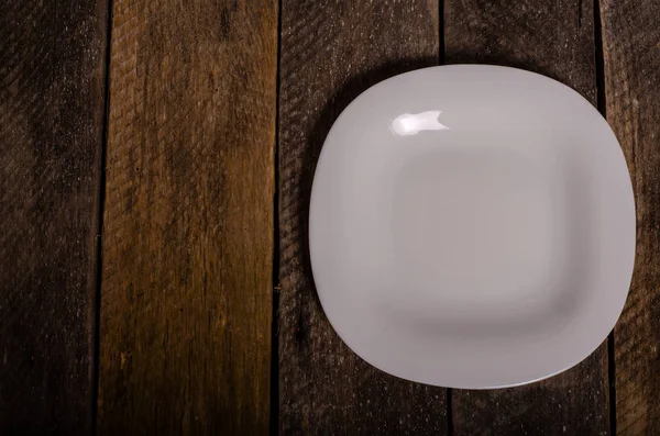 Top view of blank white dish and white tablecloth on a wood background with copy space — Stock Photo, Image