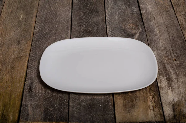 Top view of blank white dish and white stablecloth on a wood background with copy space — стоковое фото
