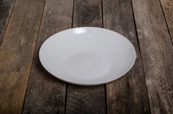 Vista superior do prato branco em branco e toalha de mesa branca em um fundo de madeira com espaço de cópia — Fotografia de Stock