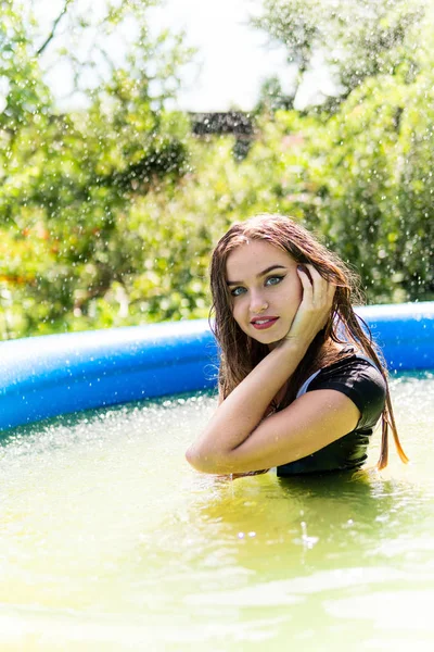 Beautiful female model dressed in long evening gowns, lies in the pool and sensually poses — Stock Photo, Image