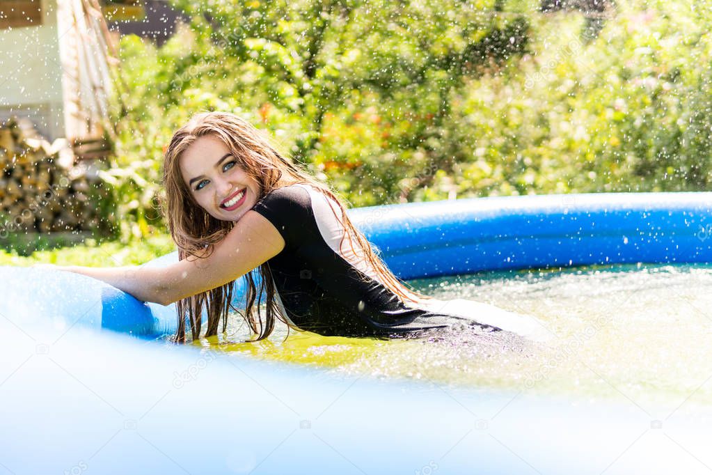 Beautiful female model dressed in long evening gowns, lies in the pool and sensually poses