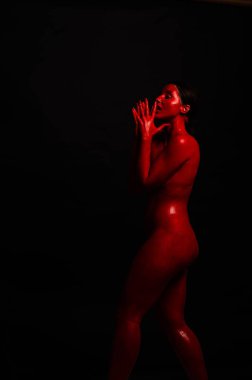 genç bir kızın yaratıcı portresi. Yüz kırmızı glitter boya ile boyanmıştır. Üçgen yüze çizilir. Siyah arka plan daki profilmodeli