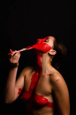 genç bir kızın yaratıcı portresi. Yüz kırmızı glitter boya ile boyanmıştır. Üçgen yüze çizilir. Siyah arka plan daki profilmodeli