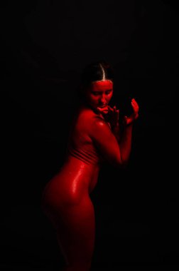 genç bir kızın yaratıcı portresi. Yüz kırmızı glitter boya ile boyanmıştır. Üçgen yüze çizilir. Siyah arka plan daki profilmodeli