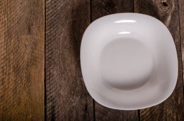 Kopya alanı ile ahşap arka plan üzerinde boş beyaz çanak ve beyaz masa örtüsü üst görünümü