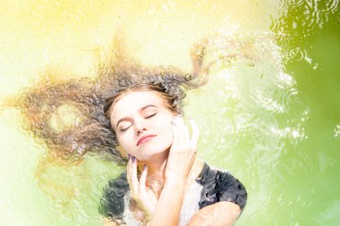 Güzel kadın model uzun akşam önlük giymiş, havuzda yatıyor ve sensually poz veriyor