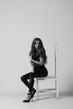 Çekici esmer güzellik sandalyede oturuyor.