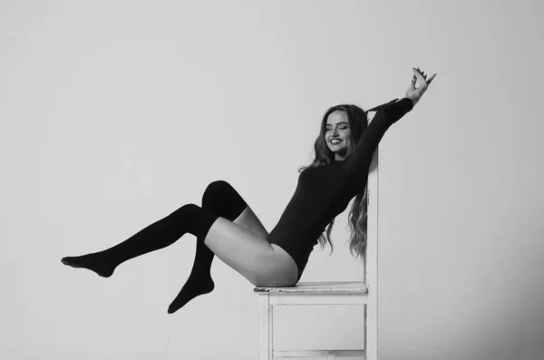 Νεαρό χαρούμενο κορίτσι γυμναστικής με σπορ σώμα που ποζάρει στο στούντιο σε μπλε φόντο. Όμορφη κοπέλα. Fitness μοντέλο σε λευκό σπορ bodysuit κάθεται στην καρέκλα. Υγιεινός τρόπος ζωής Σέξι γυναίκα.. — Φωτογραφία Αρχείου