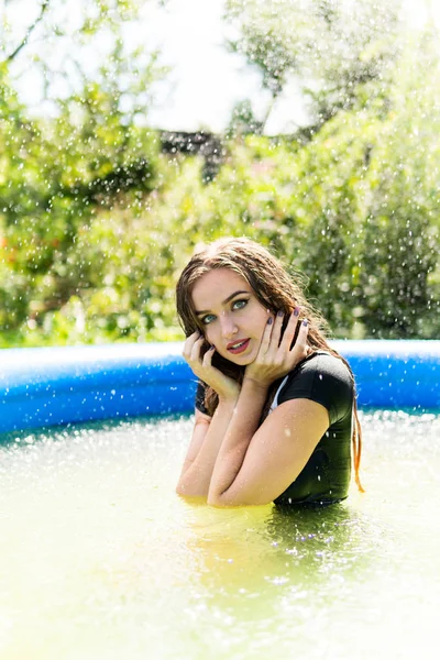 Hermosa modelo femenina vestida con largos vestidos de noche, se encuentra en la piscina y plantea sensualmente — Foto de Stock