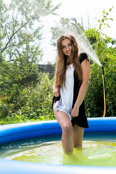 Modelo feminino bonita vestida com longos vestidos de noite, encontra-se na piscina e sensualmente poses — Fotografia de Stock