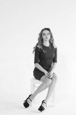 Uzun saçlı, topuklu ayakkabılı, beyaz stüdyo arka planında soyutlanmış güzel bir kadın. 