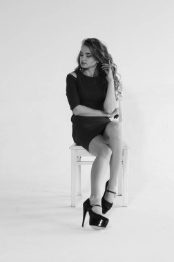 Uzun saçlı, topuklu ayakkabılı, beyaz stüdyo arka planında soyutlanmış güzel bir kadın. 