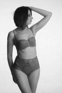 İç çamaşırlı güzel bir kadın stüdyo arkasında poz veriyor.   