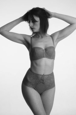 İç çamaşırlı güzel bir kadın stüdyo arkasında poz veriyor.   