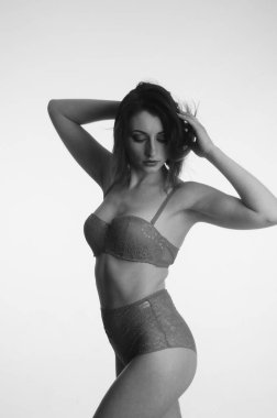 İç çamaşırlı güzel bir kadın stüdyo arkasında poz veriyor.   