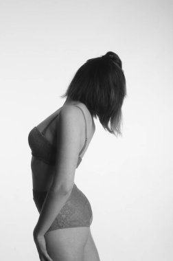 İç çamaşırlı güzel bir kadın stüdyo arkasında poz veriyor.   