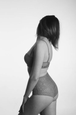 İç çamaşırlı güzel bir kadın stüdyo arkasında poz veriyor.   