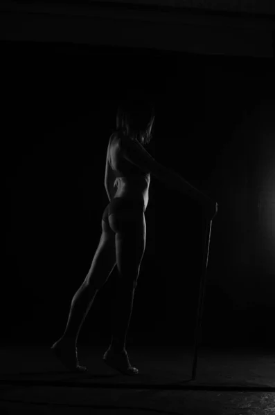 美しい女のシルエットでランジェリー姿でダークスタジオの背景にポーズ — ストック写真