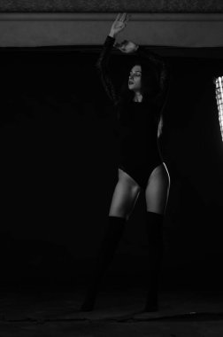 Siyah elbiseli, esmer, güzel bir kadın. Stüdyoda poz veriyor. 