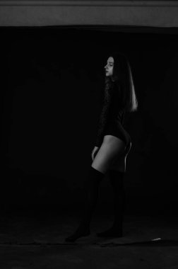 Siyah elbiseli, esmer, güzel bir kadın. Stüdyoda poz veriyor. 