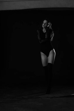 Siyah elbiseli, esmer, güzel bir kadın. Stüdyoda poz veriyor. 