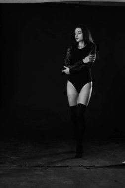 Siyah elbiseli, esmer, güzel bir kadın. Stüdyoda poz veriyor. 