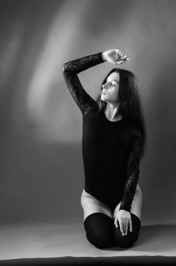 Siyah elbiseli, esmer, güzel bir kadın. Stüdyoda poz veriyor. 