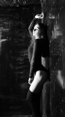 Siyah elbiseli genç bir kadın koyu bir arka planda poz veriyor, siyah saçlı ve kaslı bir spor figürü..