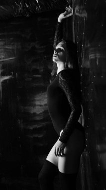 Siyah elbiseli genç bir kadın koyu bir arka planda poz veriyor, siyah saçlı ve kaslı bir spor figürü..