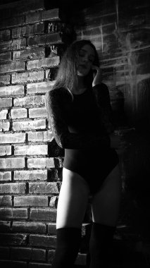 Siyah elbiseli genç bir kadın koyu bir arka planda poz veriyor, siyah saçlı ve kaslı bir spor figürü..