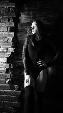 Siyah elbiseli genç bir kadın koyu bir arka planda poz veriyor, siyah saçlı ve kaslı bir spor figürü..