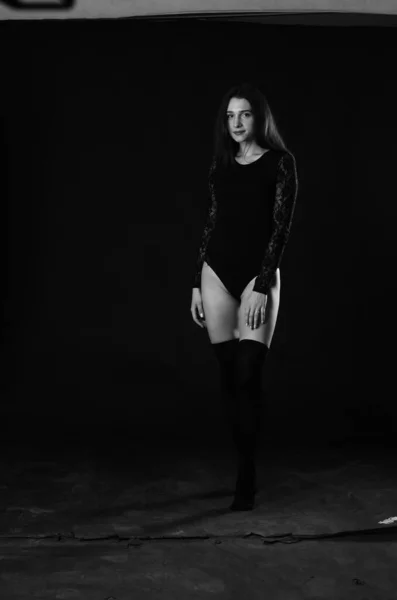 美しいですブルネット若いです女性で黒ボディスーツPosingオンダークスタジオの背景 — ストック写真