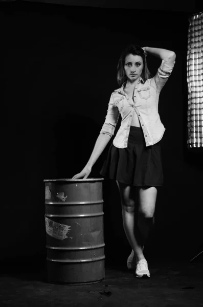 beautiful woman with short hear in stylish clothes posing with barrel on dark studio background