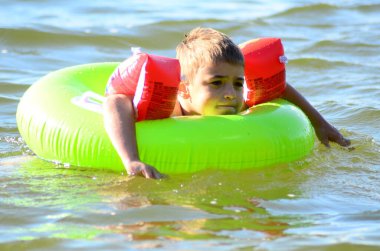 Küçük çocuk gölde yüzüyor. 