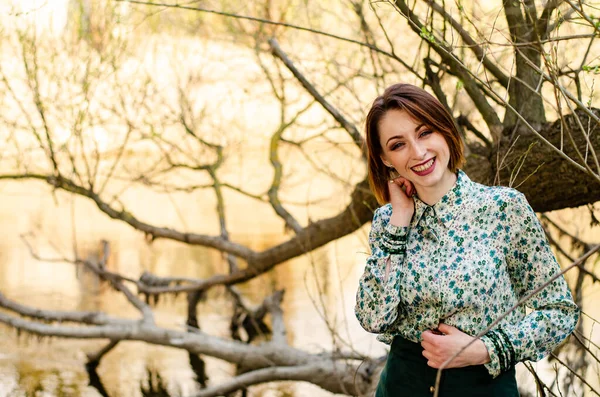 Güneşli bir günde nehir kıyısında şık kıyafetler içinde poz veren güzel esmer kadın.