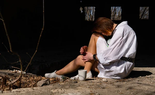Terk edilmiş bir yerde oturan beyaz gömlekli güzel bir kadın.