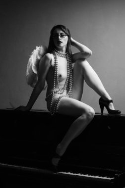 Dekoratif melek kanatları takan çıplak bir kadın. Karanlık arka planda poz veriyor.    