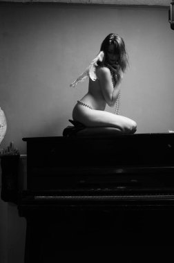 Dekoratif melek kanatları takan çıplak bir kadın. Karanlık arka planda poz veriyor.    