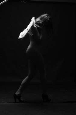 Dekoratif melek kanatları takan çıplak bir kadın. Karanlık arka planda poz veriyor.    