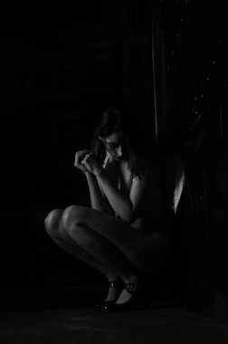 Dekoratif melek kanatları takan çıplak bir kadın. Karanlık arka planda poz veriyor.    